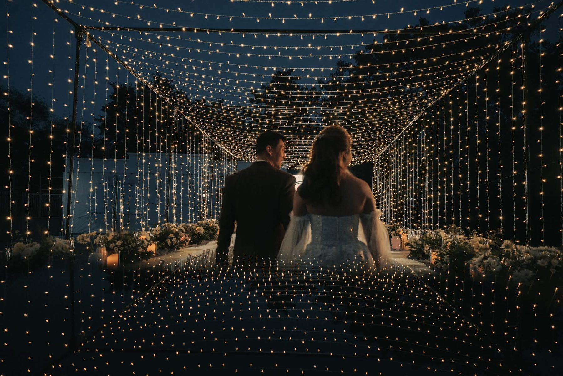 A couple beneath a canopy of lights